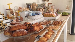 A bakery display with various pastries and bread, including croissants and muffins, arranged on trays.