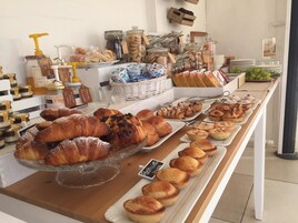 Mostrador de panadería con diversos pasteles y pan, incluyendo croissants y muffins, dispuestos en bandejas.
