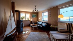 Ein Wohnzimmer mit Kamin, einer Couch, einem Couchtisch, einem gestreiften Sessel und einem Modell eines Segelbootes.