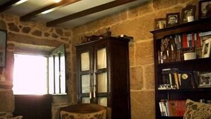 A room with stone walls, a wooden cabinet, and a bookshelf. - Casal de Folgueiras (Meis)