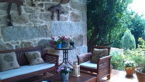 A stone wall with a rustic wooden bench and a small table with a potted plant. - Casal de Folgueiras (Meis)