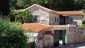 A stone building with a tiled roof, surrounded by trees. - Casal de Folgueiras (Meis)