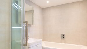 A modern bathroom with a glass-enclosed shower, a white sink, and a bathtub. - Access Tower Hill (London)