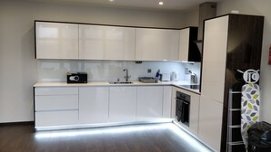 A modern kitchen with white cabinets, a built-in oven, and a microwave on the countertop. - Access Tower Hill (London)
