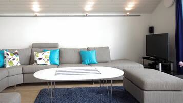 A modern living room with a grey sectional sofa, a white coffee table, and a flat-screen TV.