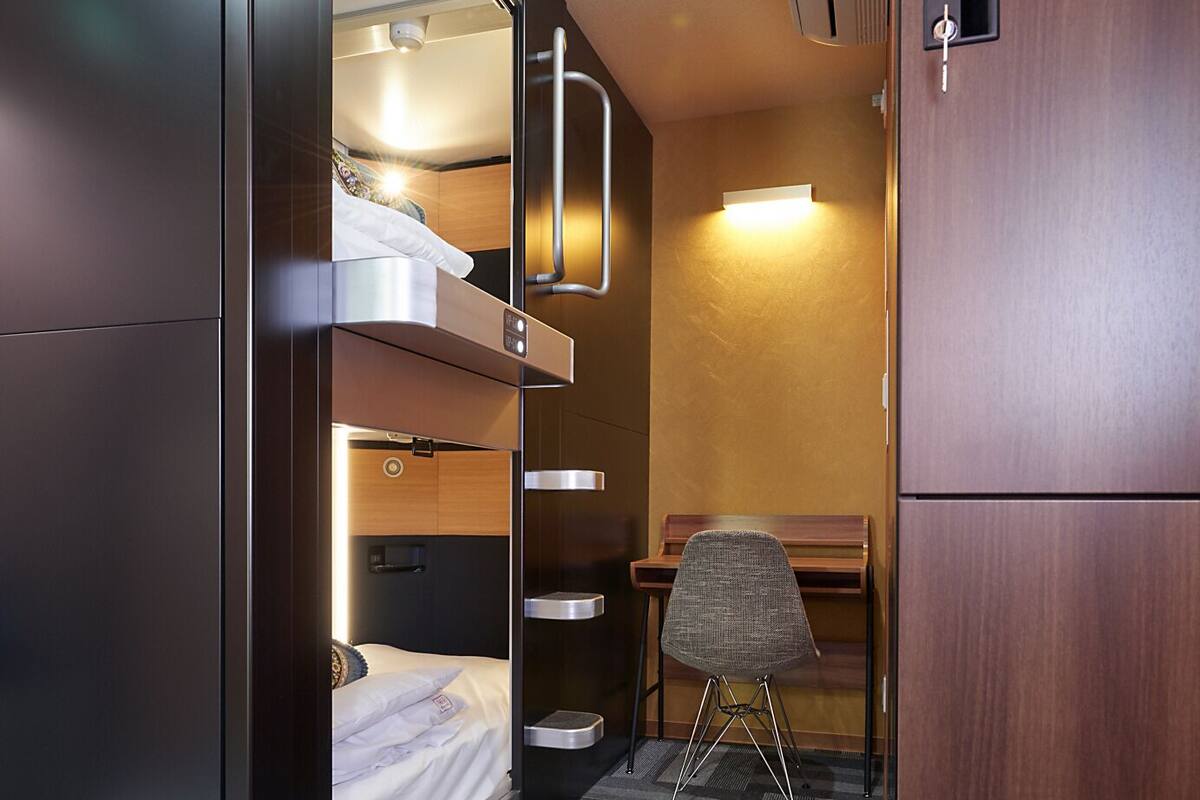 Una habitación de hotel pequeña con una cama litera, un escritorio y una silla.