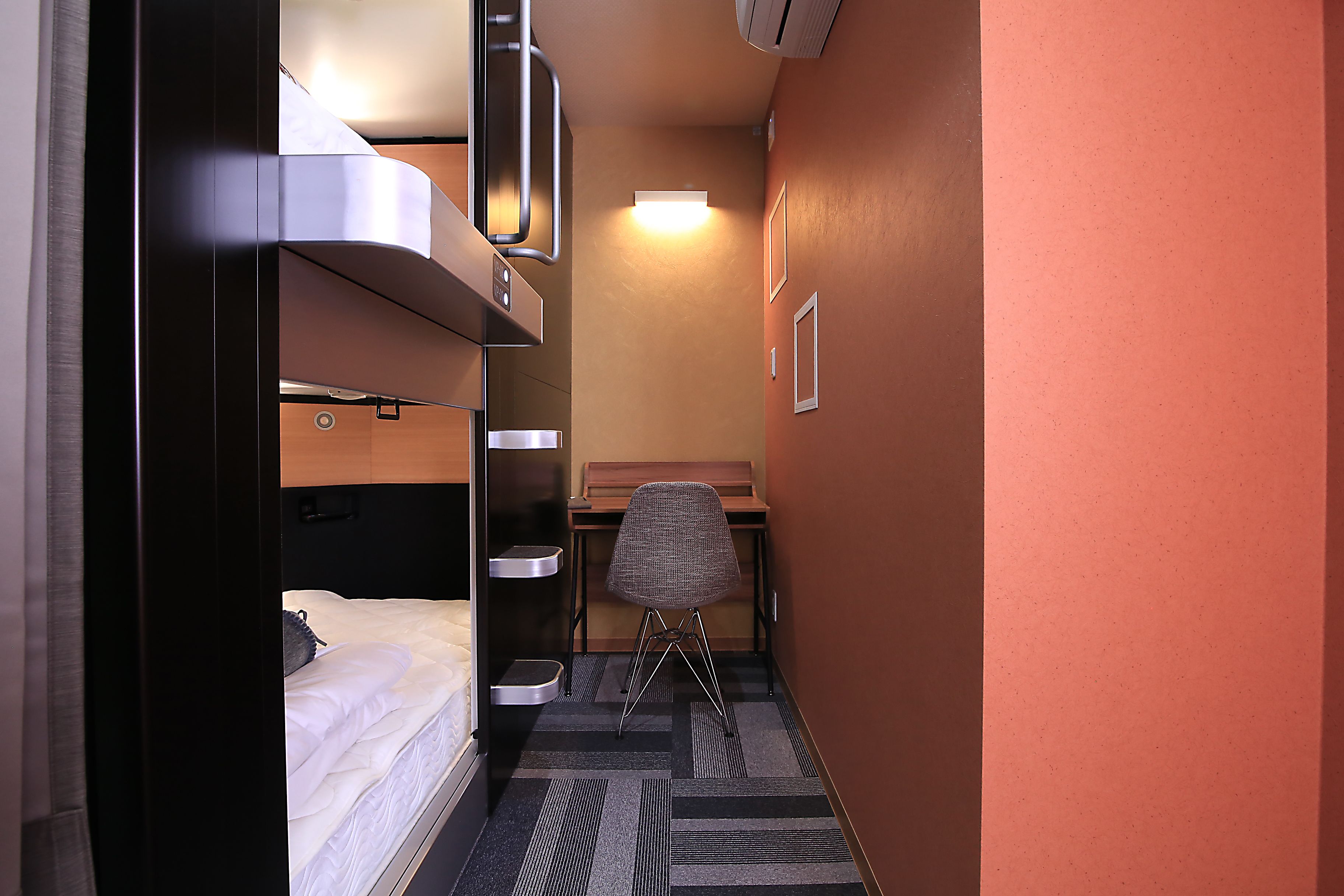 Una habitación de hotel compacta con una cama litera, un escritorio y una silla.