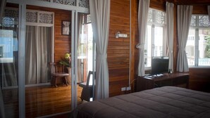Una habitación con cama, televisor, escritorio y silla.