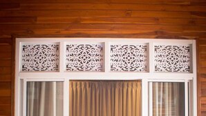 Una habitación con cama, cortinas y suelo de madera.