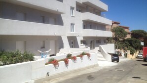 A modern multi-story building with balconies, a staircase, and a parking area. - Rena Bianca Suite (Santa Teresa di Gallura)