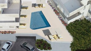 An aerial view of a residential building with a swimming pool, outdoor seating, and a parking area. - Rena Bianca Suite (Santa Teresa di Gallura)