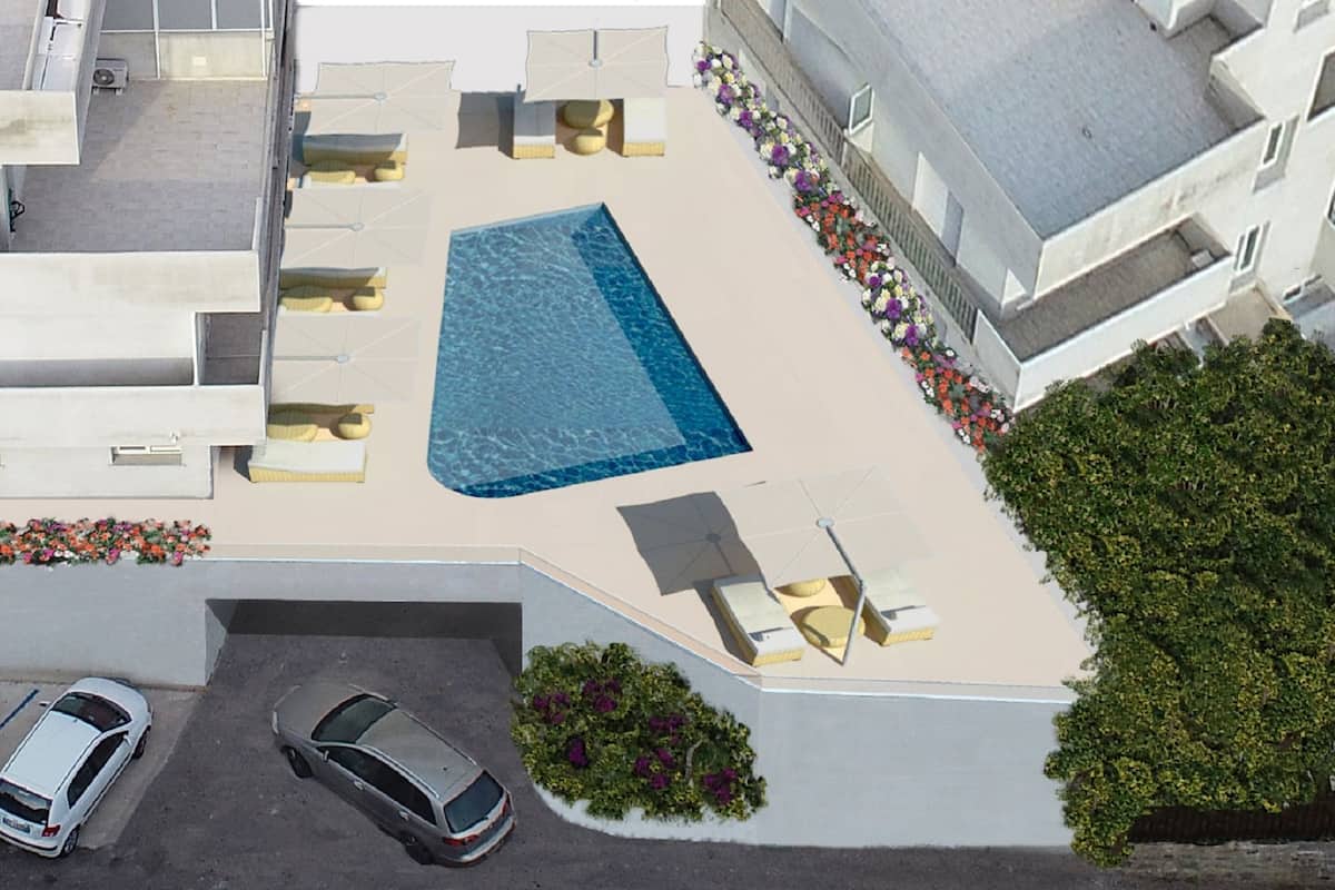 An aerial view of a residential building with a swimming pool, outdoor seating, and a parking area.