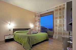 Une chambre à coucher avec un lit, une table de chevet et une vue sur l’extérieur.