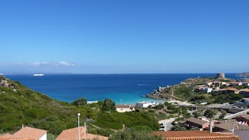 Uma cidade costeira com um castelo histórico, mar azul cristalino e edifícios com telhados de terracota.