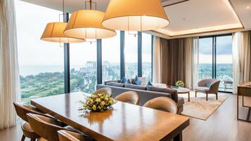 A modern hotel room with a dining area, large windows with a city view, and a sofa set.