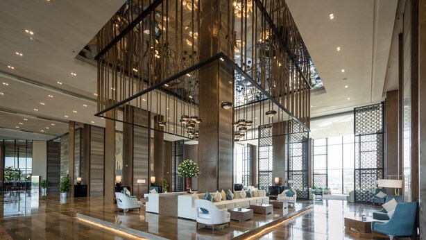 A spacious lobby with a central seating area, large windows, and modern lighting fixtures. - FLC Grand Hotel Samson (Sam Son)