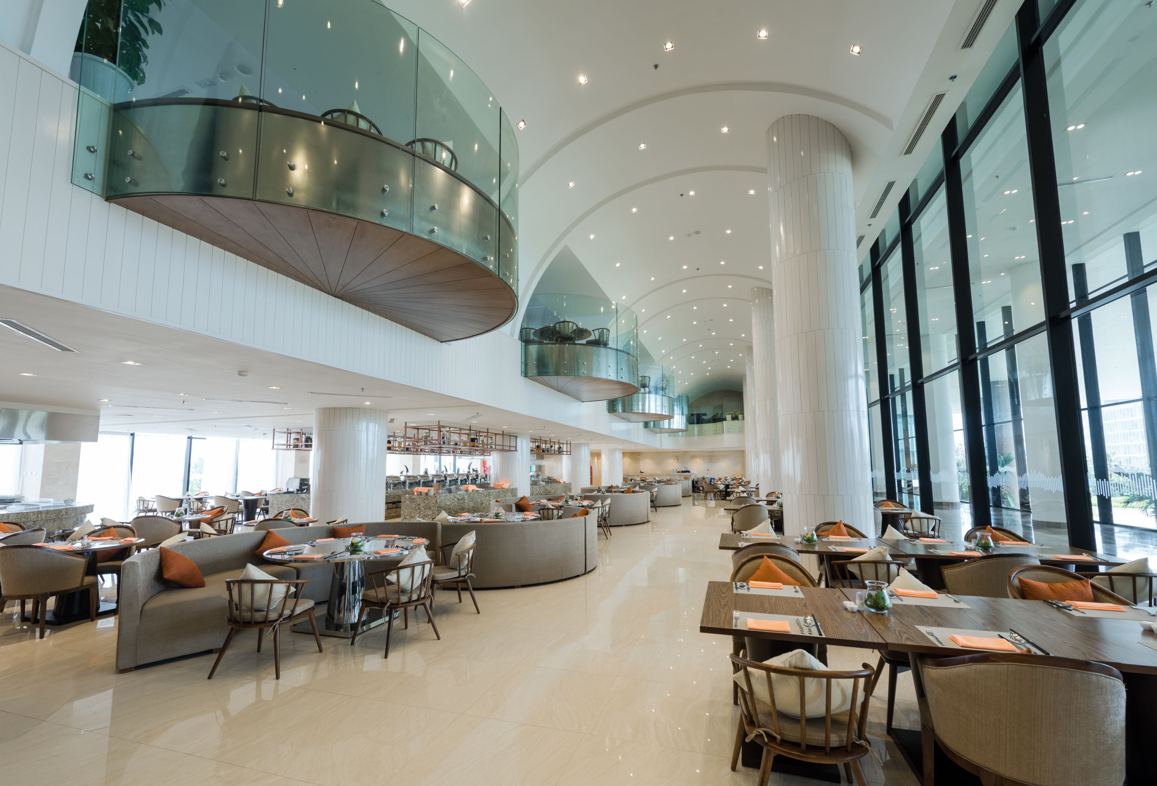 A spacious hotel lobby with multiple seating areas, a central bar, and large windows offering views.