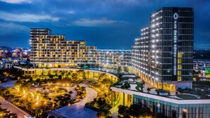 A modern hotel complex with multiple high-rise buildings, a landscaped courtyard, and illuminated windows. - FLC Grand Hotel Samson (Sam Son)