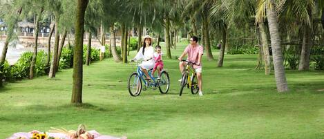 Una familia en bicicleta en un parque, con una preparación para picnic.