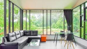 A modern living room with a leather sofa, glass coffee table, and a dining area with chairs and a table. - Nana River Kaeng Krachan (Kaeng Krachan)