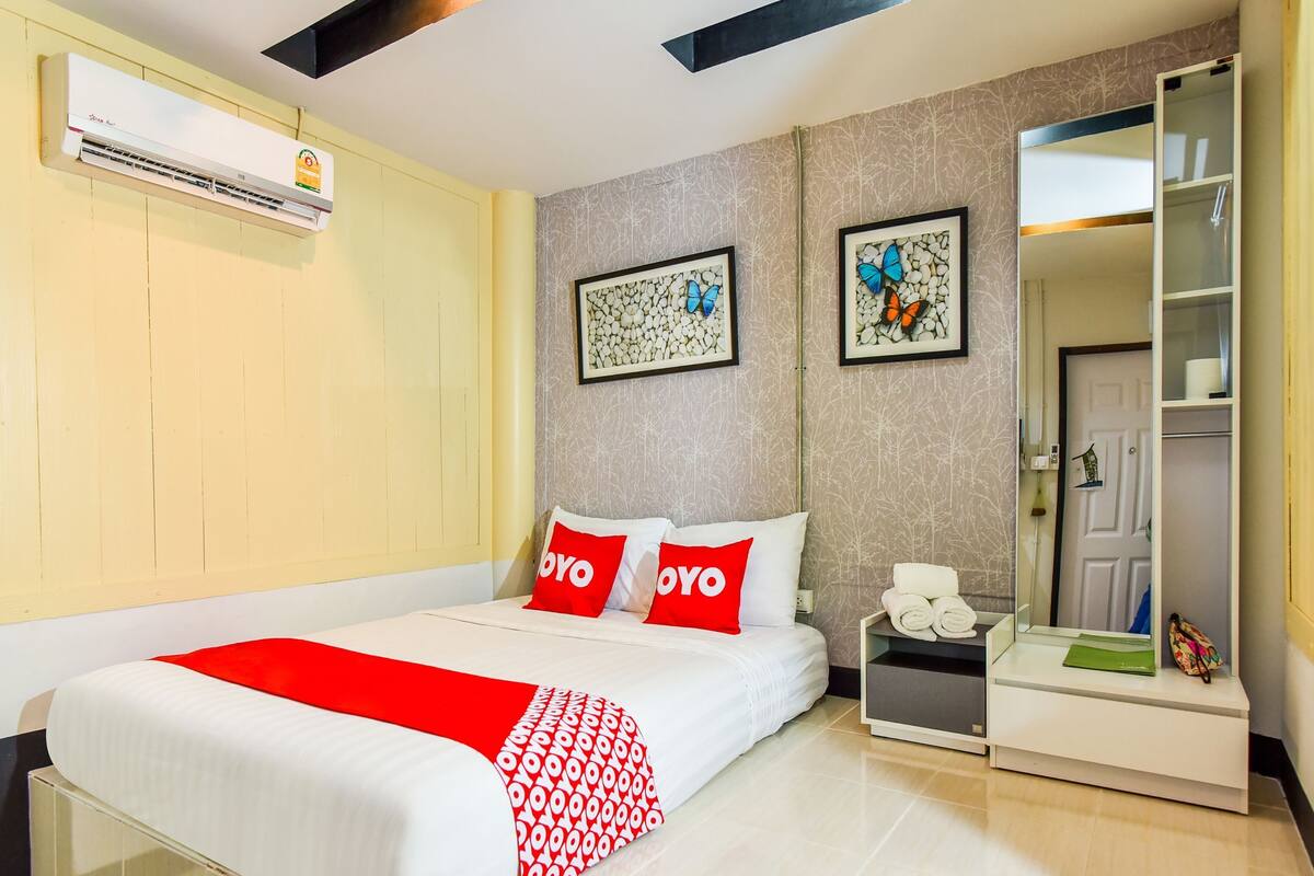 Une chambre d’hôtel comprenant un lit, une table de chevet, un miroir et une armoire.