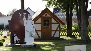 A park entrance with a white statue of a man holding a light bulb, a cat silhouette, and a sign reading "Parkplatz L". - Sunshine (7) - Landhaus Mönkebude (Mönkebude)