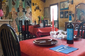 A restaurant interior with red tablecloths, wine glasses, and a bottle of wine on the table. - Arco dei Nobili (Monforte d'Alba)