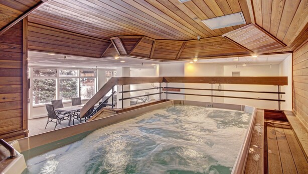 A spa with a large indoor pool, wooden ceiling, and a view of the outdoors. - Vs440h Village Square Hotel Room (Copper Mountain)
