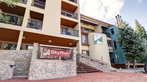 A multi-story building with a stone facade and a sign for SkyRun Vacation Rentals. - Vs440h Village Square Hotel Room (Copper Mountain)
