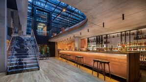 A modern bar with a curved counter, wooden flooring, and a glass ceiling. - Hotel Warszawa (Warsaw)