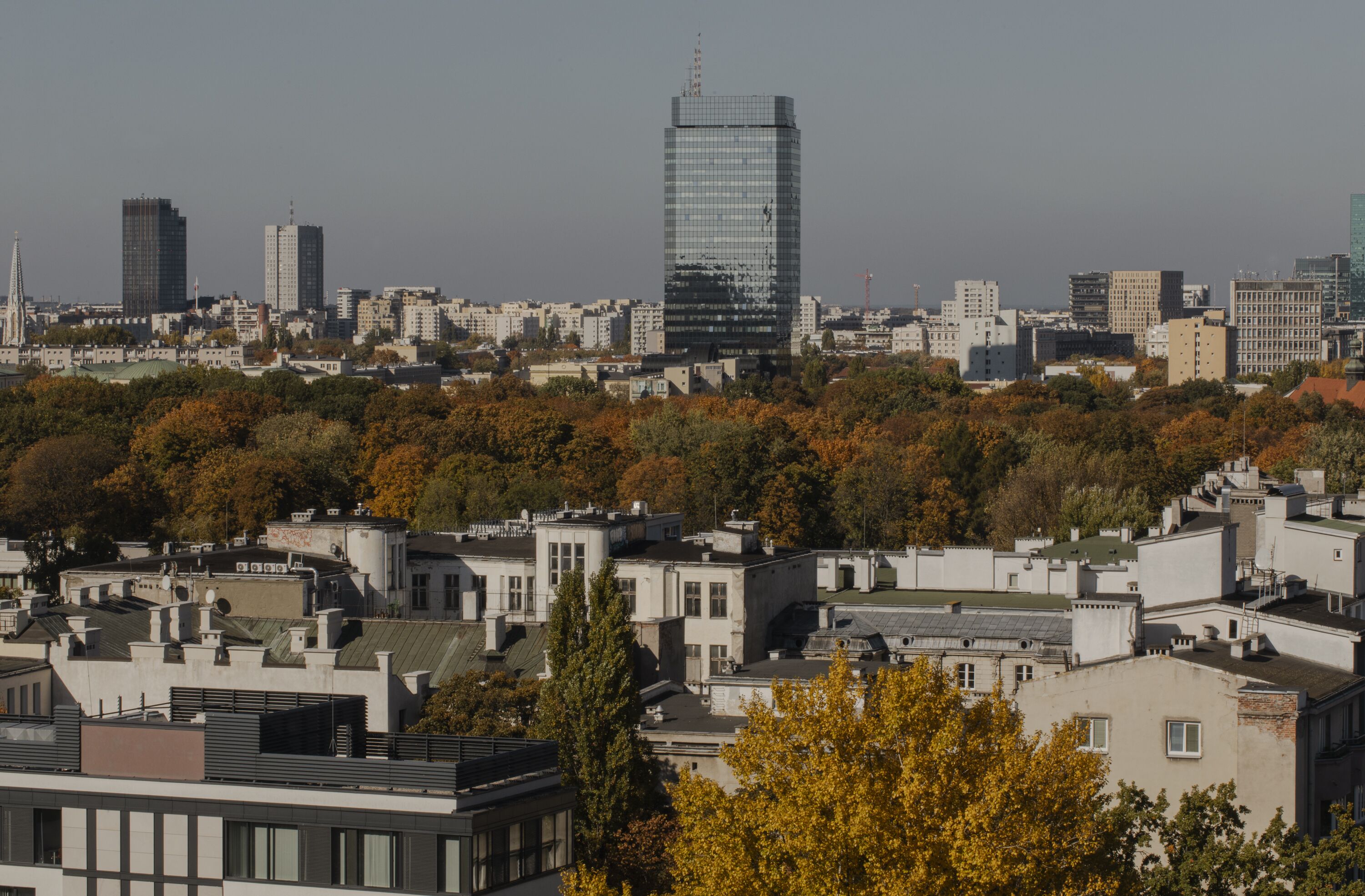 Un paysage urbain présentant une variété de bâtiments, dont un imposant gratte-ciel moderne et plusieurs constructions plus anciennes.