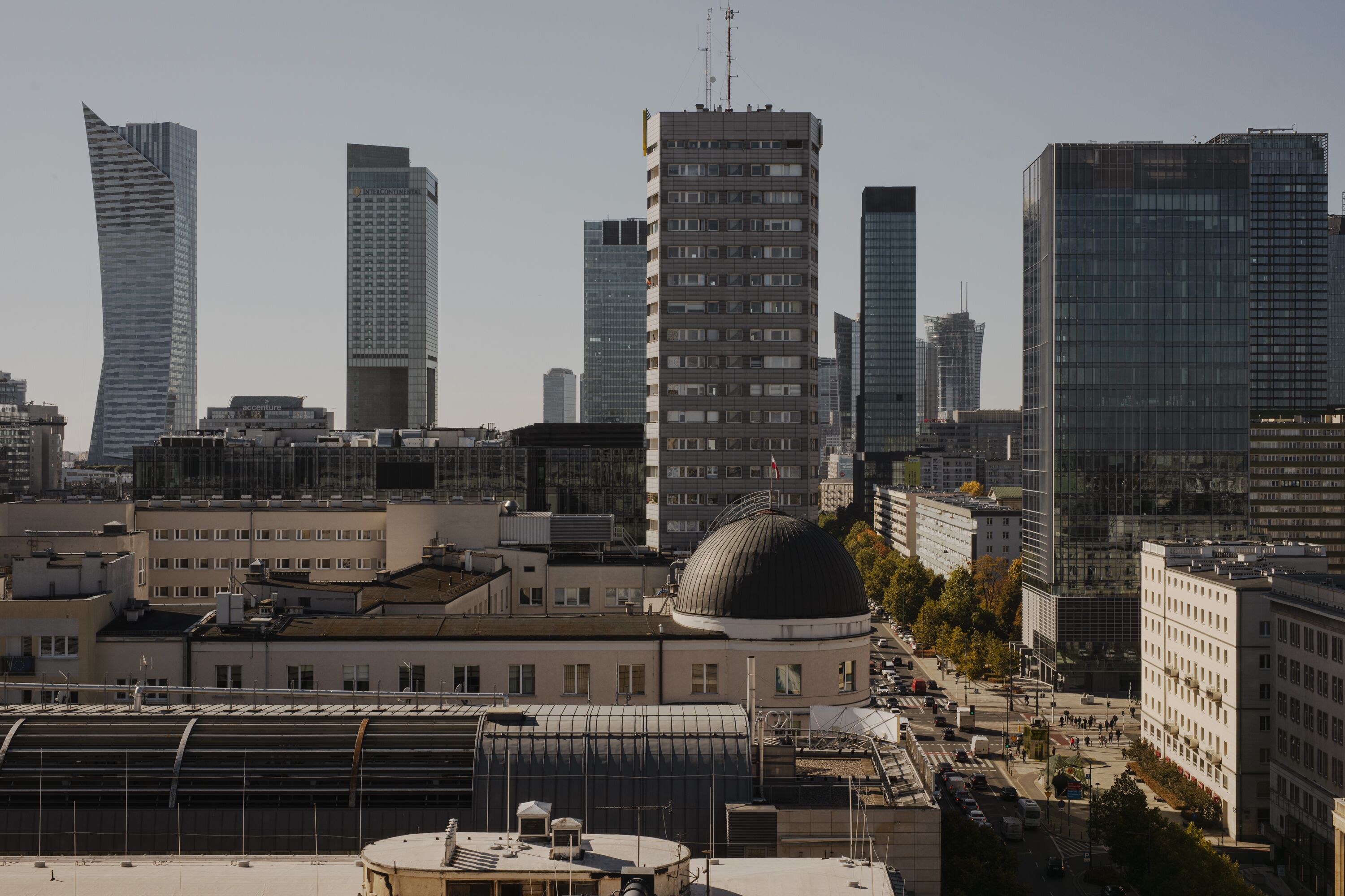En stadsbild med moderna skyskrapor, en framträdande byggnad i form av en kupol och en blandning av höga och medelhöga byggnader.