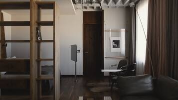 Una habitación moderna con una estantería de madera, un escritorio, un sofá de cuero y un ventanal con cortinas.
