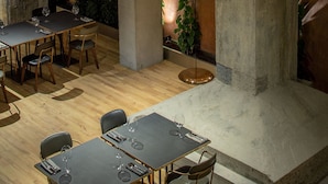 A modern interior with a dining area, high ceilings, and exposed concrete elements. - Hotel Warszawa (Warsaw)
