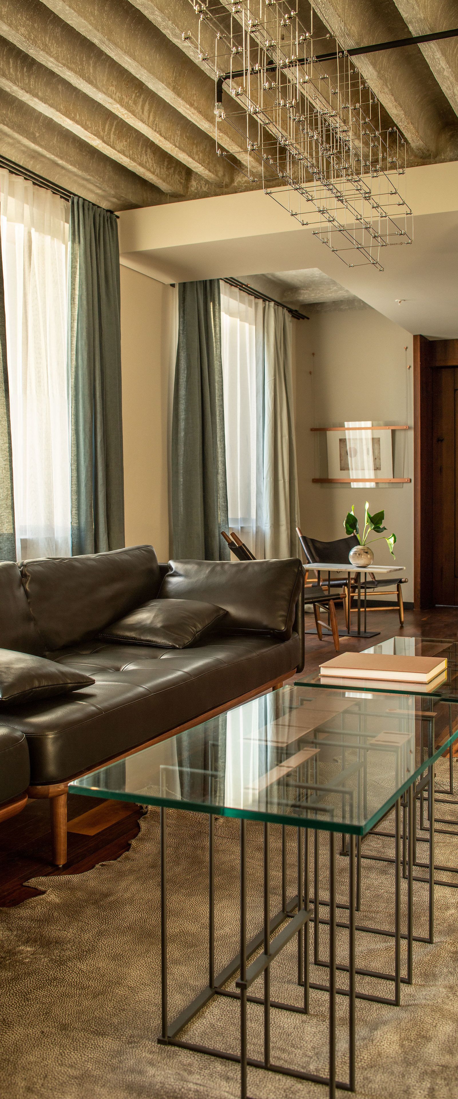A modern living room with a leather sofa, glass coffee table, and a dining area with a table and chairs.