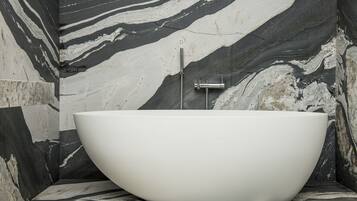 Ein modernes Badezimmer mit freistehender Badewanne, Marmorwänden und einem minimalistischen Design.
