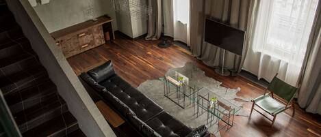 A modern living room with a leather sofa, a glass coffee table, a flat-screen TV, and a green chair.