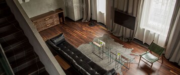 Una sala de estar moderna con un sofá de cuero, una mesa de centro de vidrio, un televisor de pantalla plana y una silla verde.