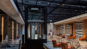 A modern interior with a glass ceiling, wooden flooring, and seating areas. - Hotel Warszawa (Warsaw)