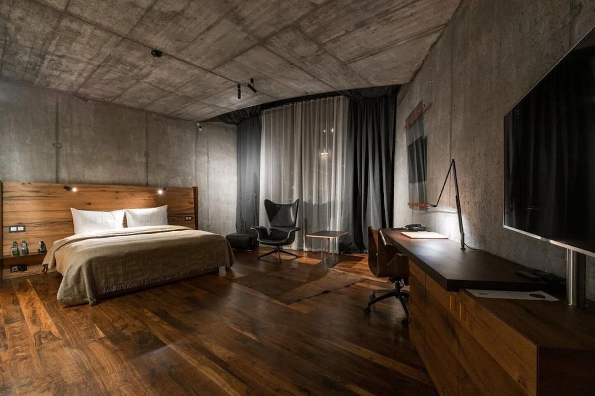 A modern bedroom with a wooden bed, a desk, and a large TV.