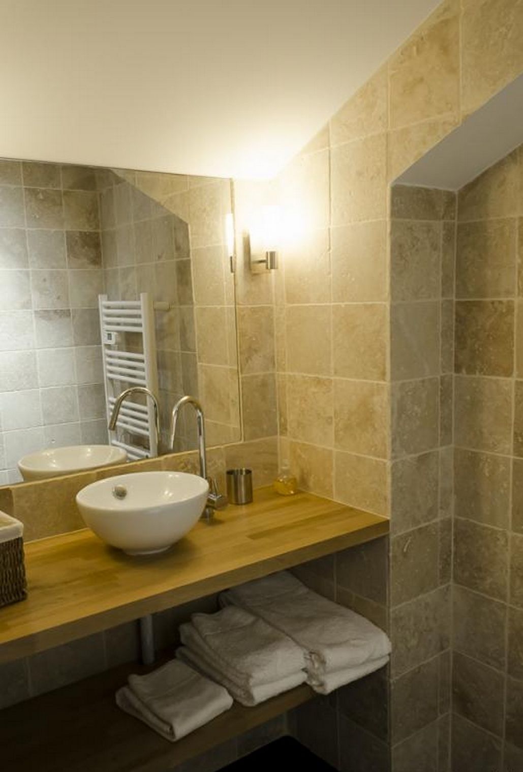Een badkamer met een houten wastafelmeubel, twee wastafels, een handdoekrek en een douchehoek.
