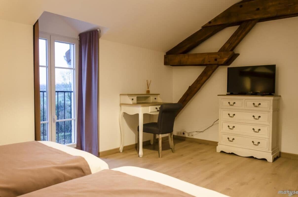 Ein Schlafzimmer mit einem Bett, einem Schreibtisch, einem Sessel, einer Kommode und einem Fernseher.