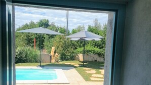Vista de un patio trasero con una piscina, dos sombrillas y una silla de metal.
