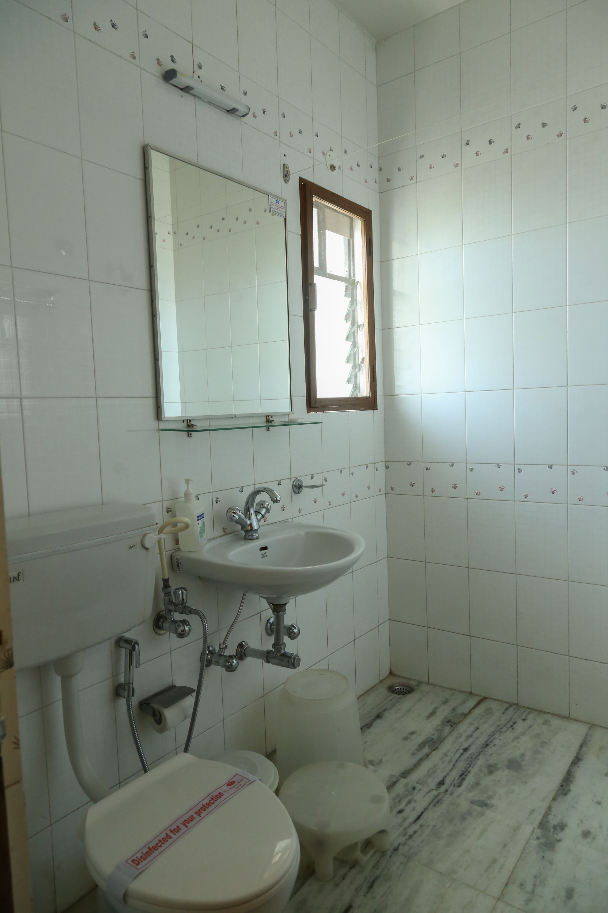 A bathroom with a white sink, mirror, toilet, and tiled walls.