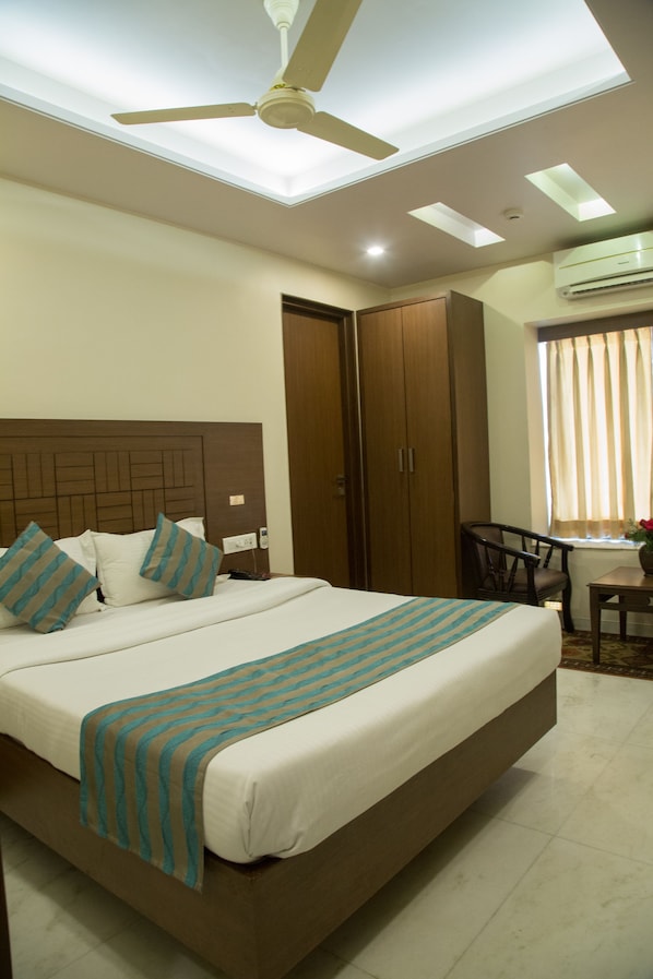 A bedroom with a bed, a ceiling fan, a wardrobe, and a window with curtains.