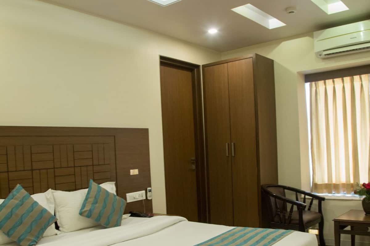 Habitación de hotel con cama, ventilador de techo, armario, escritorio y ventana con cortinas.