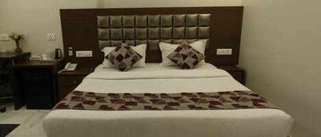 A neatly made bed with a patterned bedspread, a headboard with a tufted design, and two bedside tables with lamps and a phone.