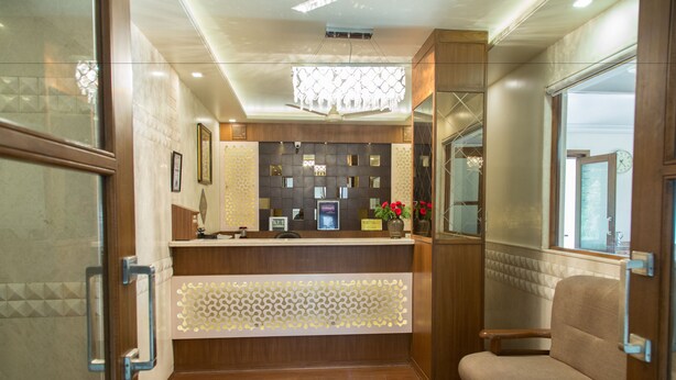 A reception area with a wooden reception desk, a chandelier, and a seating area. - The Majestic Manor (Nagpur)