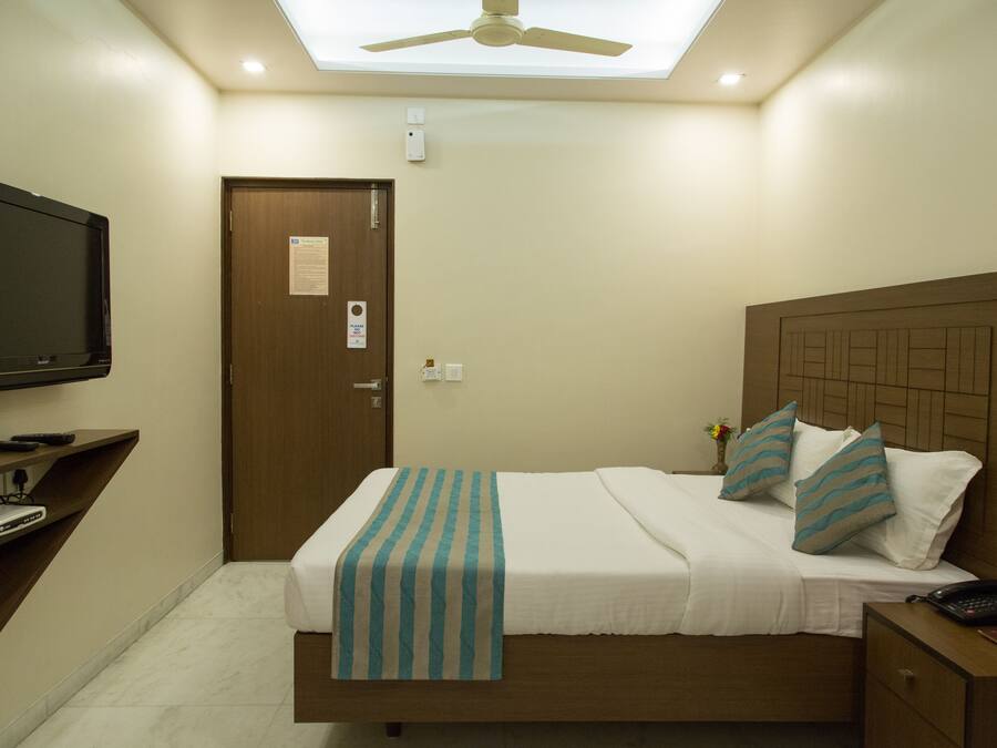 A hotel room with a bed, bedside table, TV, and a ceiling fan.