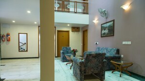 A hotel lobby with a marble floor, a seating area with patterned sofas, a glass table, and a painting on the wall. - The Majestic Manor (Nagpur)